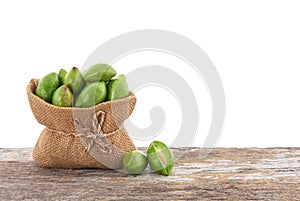 Terminalia chebula or chebulic myrobalans fruits in sack on the wooden table with clipping path