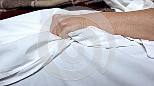 Terminally-ill woman clenching bedsheets feeling terrible pain, death convulsion photo