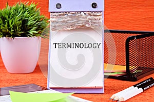 TERMINOLOGY text written on the page of the desktop calendar on an orange background photo