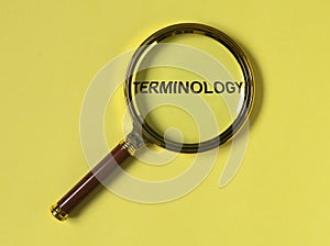 Terminology word through magnifier on bright yellow background, top view