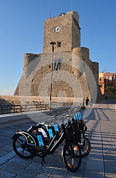 Termoli, Molise, Italy -08-29-2022- Electric bike sharing stationl in front of the Swabian castle with a young couple in the