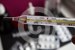 A termometr with high temperature and different medicines on background photo