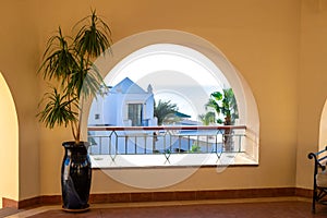 Terrace with arch overlooking the sea. Tall plant in a pot on a spacious balcony. A semicircular window overlooking the villa and