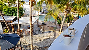 Terrace in coastal paradise, chairs and tables next to pool seen from balcony