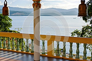 Terrace with columns, Buddhist bells, view of the sea and mountains in the distance