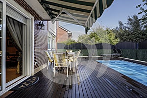 Terrace with covered pool of a single-family home with acacia wood floors, an outdoor dining table with matching chairs and a