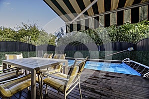 Terrace with covered pool of a single-family home with acacia wood floors, an outdoor dining table with matching chairs and a