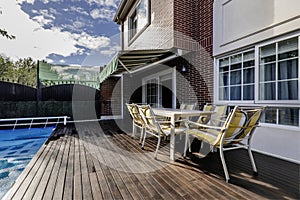 Terrace with covered pool of a single-family home with acacia wood floors, outdoor dining table with matching chairs and