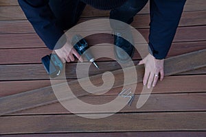 Terrace deck worker holding power screwdriver and wood timber plank, wooden decking industry and building