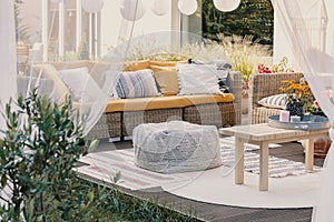 Terrace design idea with rattan garden furniture set and cozy pillows and rug, real photo