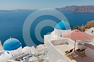 Terrace with nobody on two deck chairs in the greek island of Satorini with the best landscape of the Aegean sea and the Caldera