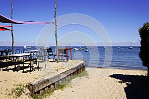 Terrace oyster restaurant seaside with empty chairs and wood table on beach village of l`herbe in Cap Ferret France