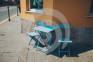A terrace with a small blue table and chairs. cosy street with colorful chairs in the city.
