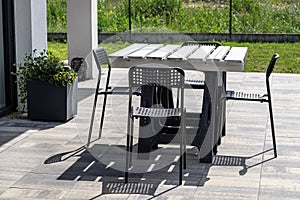 Terrace table made of white pallet standing on plastic trestles, black plastic chairs.