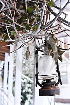On the terrace of a wooden house hangs an old lantern lantern with a decor of dry branches