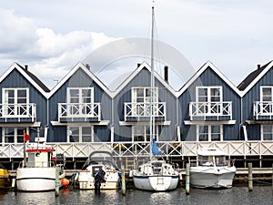 Terraced houses at a harbor next to the water with yachts in the foreground