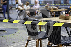 Terraces in the city open again. Safety barrier tape on a terrace. People sitting on terrace in background