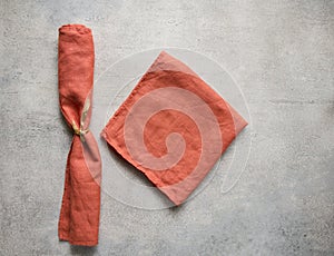 Terracotta folded linen napkins on gray concrete table with copy space, top view