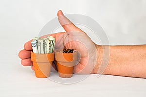 Terracotta pot with rolled up money, change and hand behind it