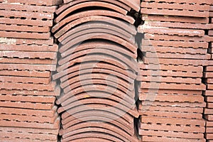 Terracotta roof tiles stacked ready for use with a symmetrical pattern