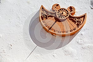 Terracotta sundial on a white wall of a house. Intense sun