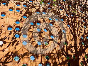 Terracotta ventilation circular brick block wall with circle space pattern wall background with tree shade.