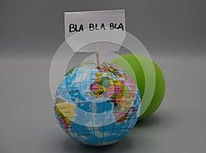 A terrestrial globe holding a sign,reading, bla bla bla,next to a green sphere. Concept of discussion about climate in Glasgow