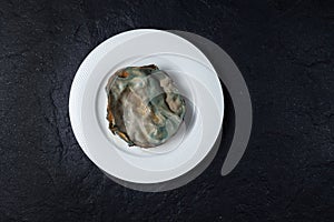 Terrible expired food covered with mold on white plate, top view. Dark background made of natural stone, copy space. Concept -