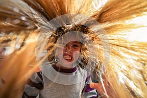 A terrible and frightening children`s witchcraft portrait. The child makes an angry face. A small evil girl with long disheveled