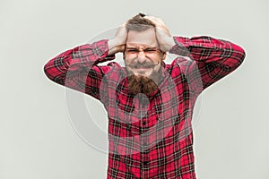 Terrible headache. Young adult man touching his head with hands