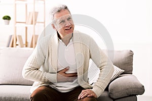 Terrible stomachache. Senior man hugging his belly, suffering from pain photo