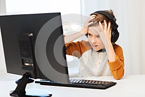 Terrified boy with computer and headphones at home