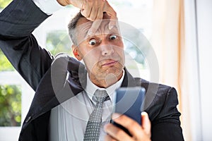 Terrified Businessman Looking At Mobile Phone Screen