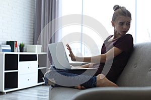 Terrified teenage girl with laptop in room