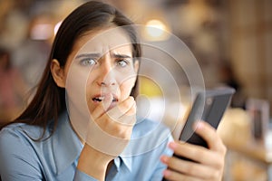 Terrified woman holding phone in a bar