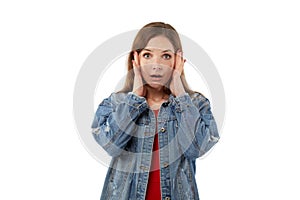 A terrified young woman looks at the camera and holds her head in her hands.