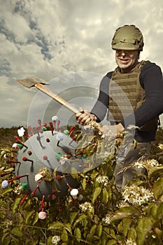 Territorial army member fighting with model of coronavirus virion outdoor on meadow