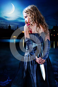 Terror girl holding knife at moonlit lake.