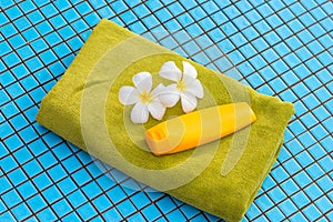 terry towel, sunscreen cream and two plumeria flowers from above