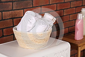 Terry towels in basket on white washing machine indoors. Laundry room interior design