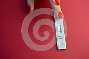 Test for coronavirus lies on a red background. a girl with a red manicure applies a punctured finger to take blood. sensitive test