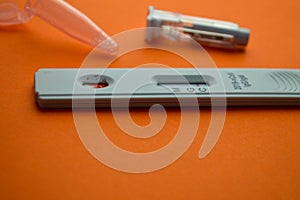 Test for coronavirus on an orange background. on a matte background, a sensitive strip for coronavirus, a lancet, a container for
