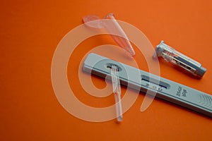 Test for coronavirus on an orange background. on a matte background, a sensitive strip for coronavirus, a lancet, a container for