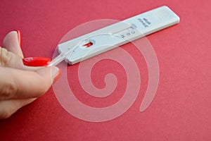 Test for coronavirus on a red background. girl with a bright red manicure makes a blood test. determination of IgG and IgM