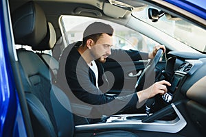 Test drive for auto. Pleasant overjoyed handsome boy holding steering wheel and driving his car while expressing gladness