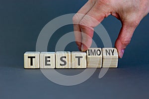 Test or testimony symbol. Businessman turns wooden cubes and changes the word `test` to `testimony`. Beautiful grey background