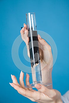 Test tube with reagents in the hands of a doctor on a blue background