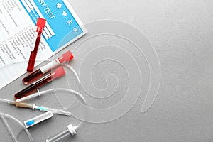 Test tubes with blood samples and medical equipment on light background, top view