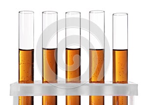 Test tubes with brown liquid in stand on white background