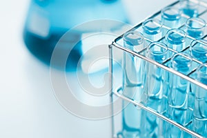 Test tubes and erlenmeyer flask filled with blue sample chemicals in chemistry science laboratory. Glassware in medical research.